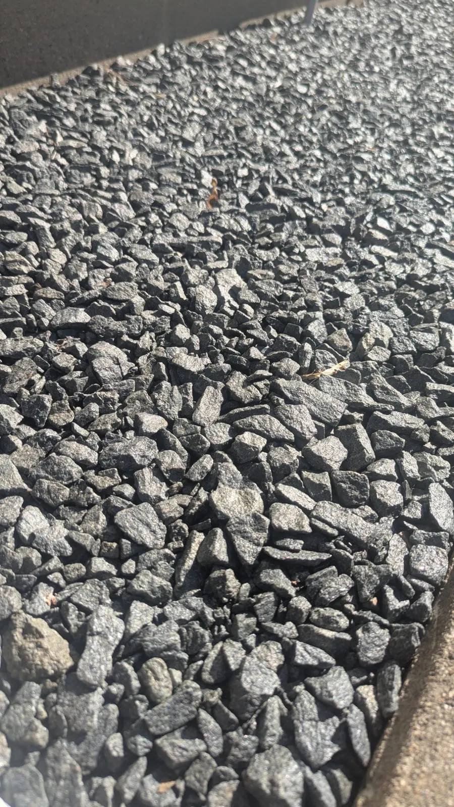 Close-up of fresh dark angular gravel in a bed along a wall