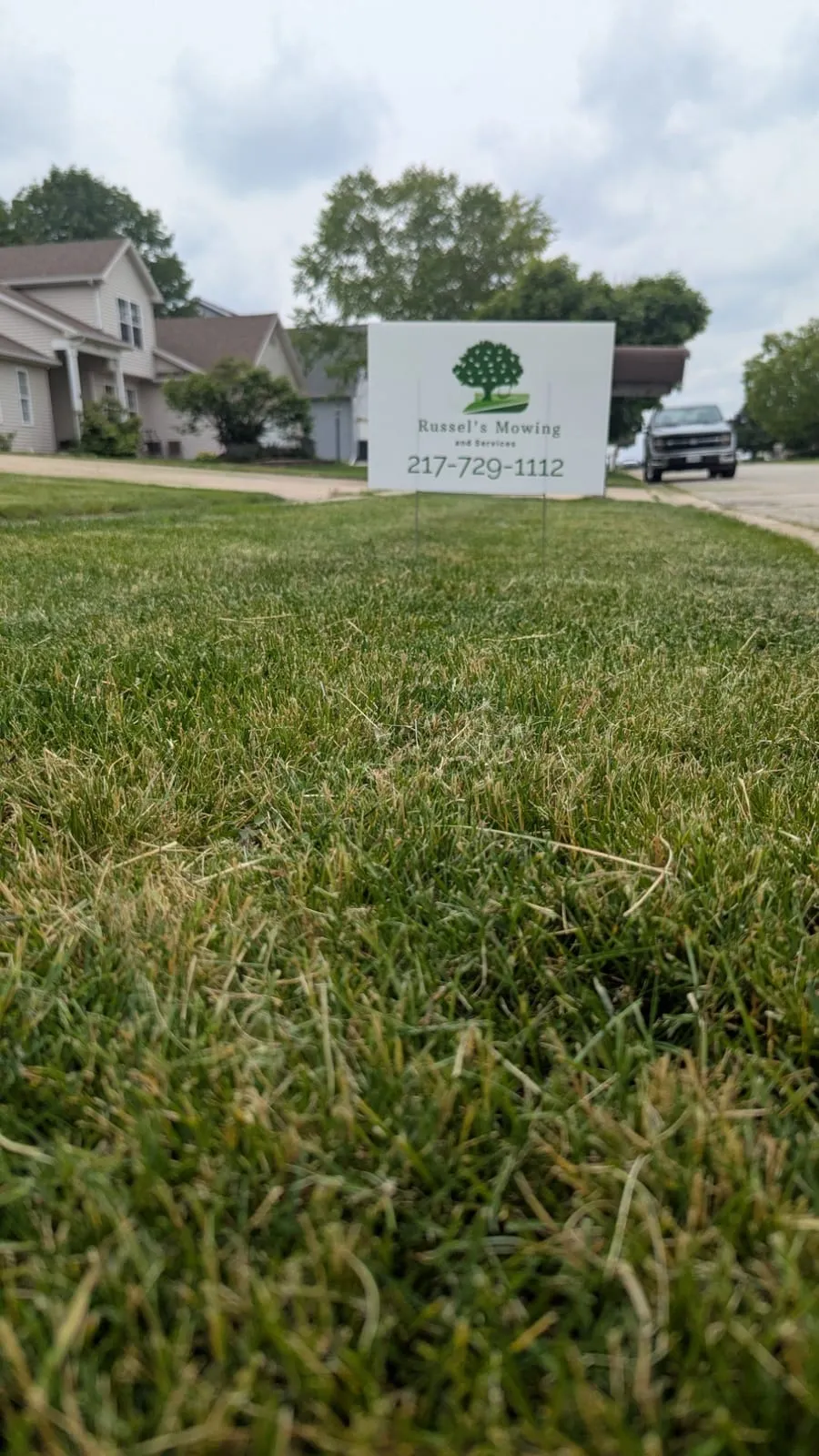 Russel's Mowing and Services yard sign with the phone number 217-729-1112 on a front lawn